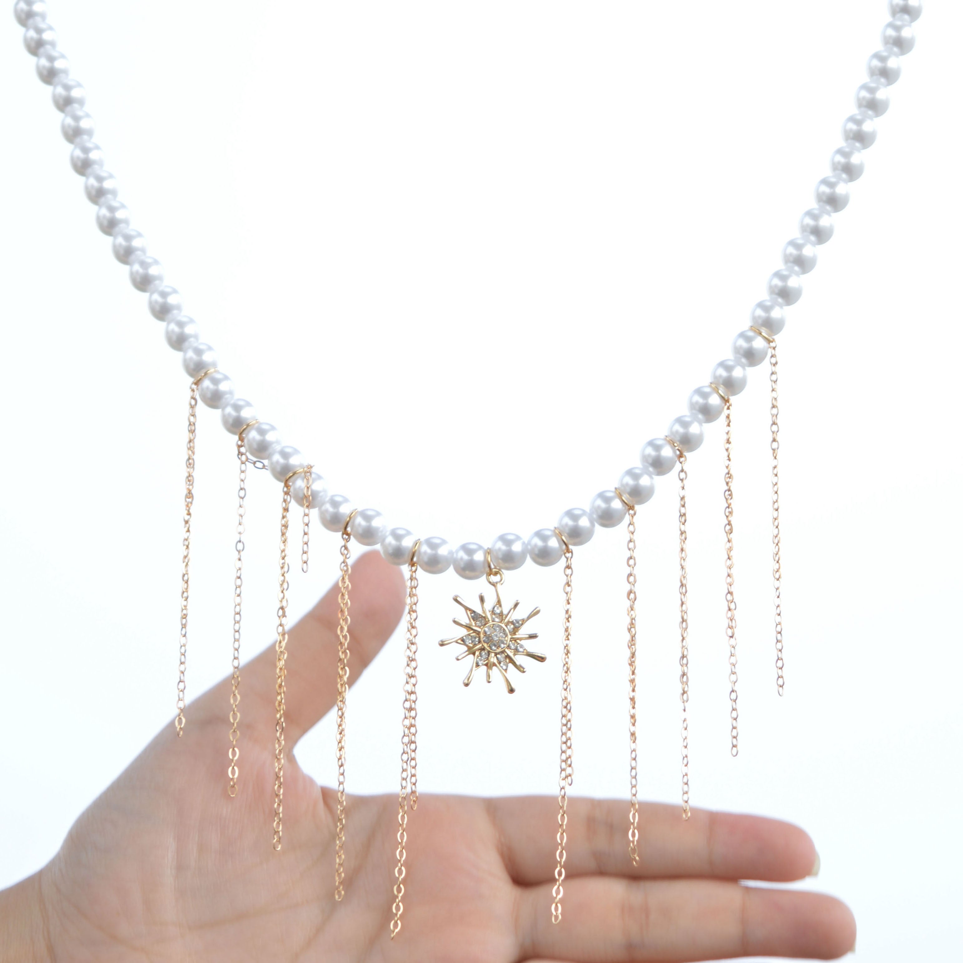 Close-up of the handcrafted crystal-encrusted sunburst pendant and the delicate attachment points of the cascading fringe chains on The Celestial Fringe necklace