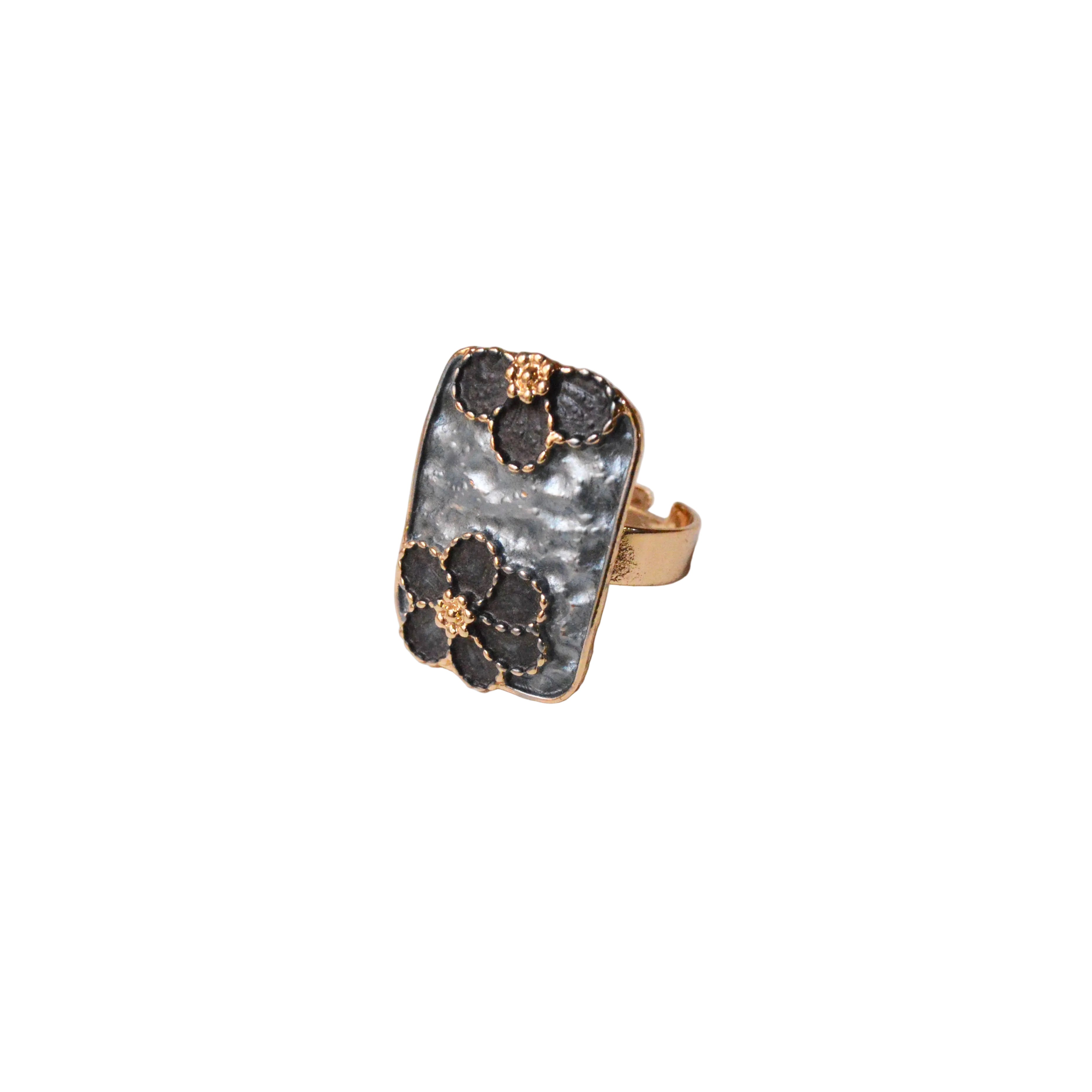 Gold ring with black gemstones on a light gray background