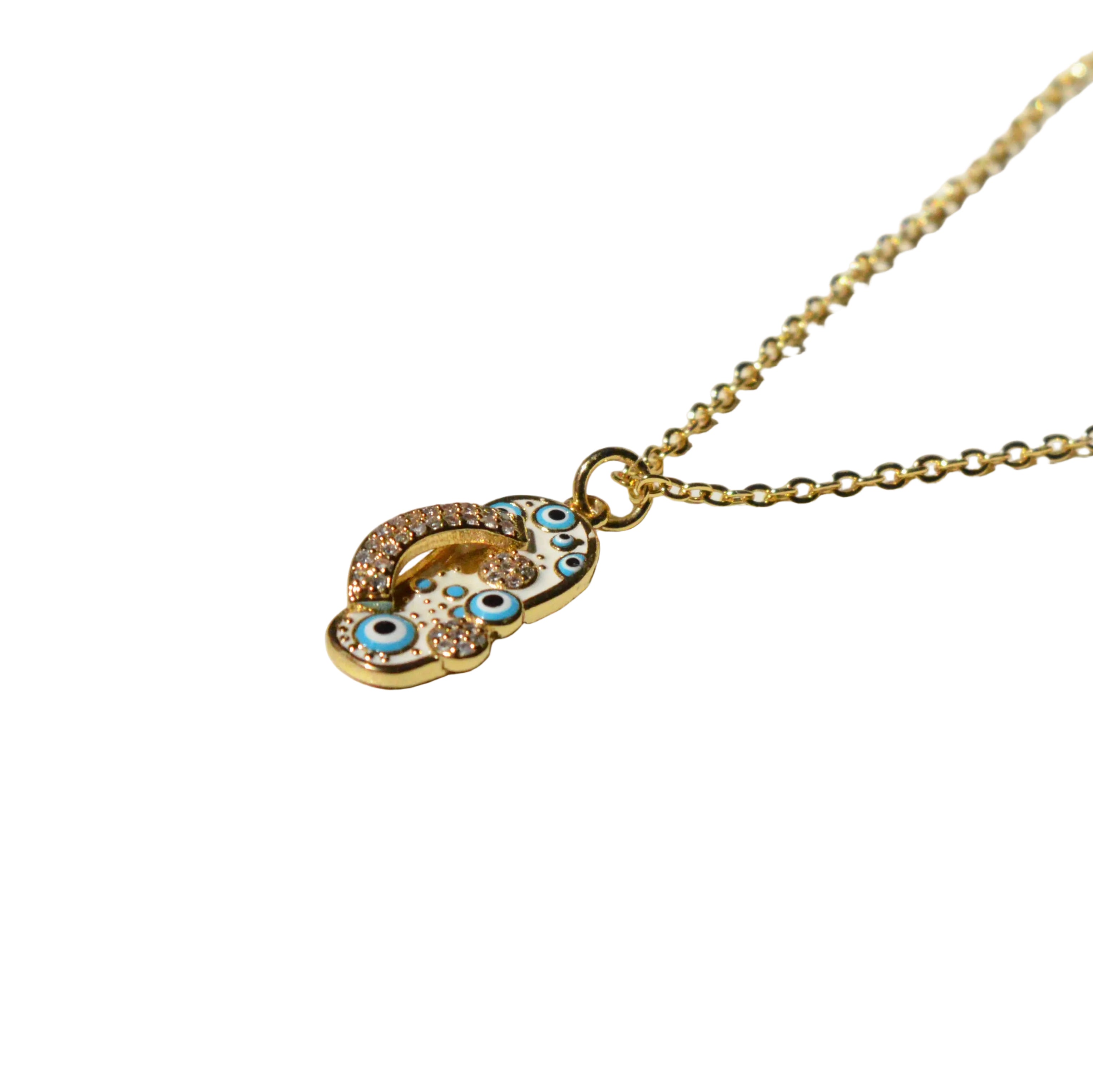 The Amulet Pendant, a gold-tone stainless steel charm featuring intricate enamel eye motifs and pavé crystal accents