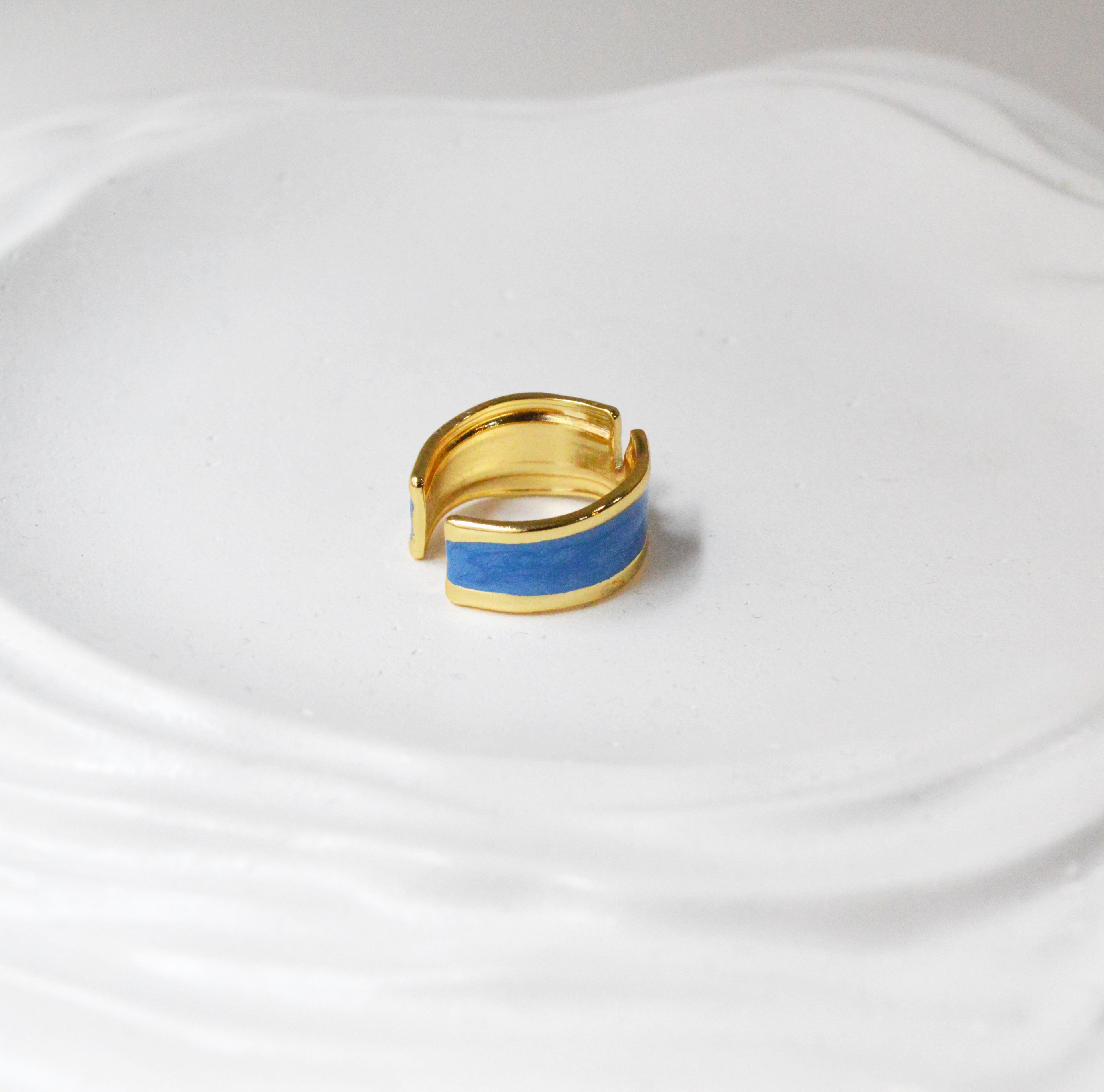 The anti-tarnish gold-toned Cyan Serene ring highlighting its unique V-cutout and marbled enamel detailing
