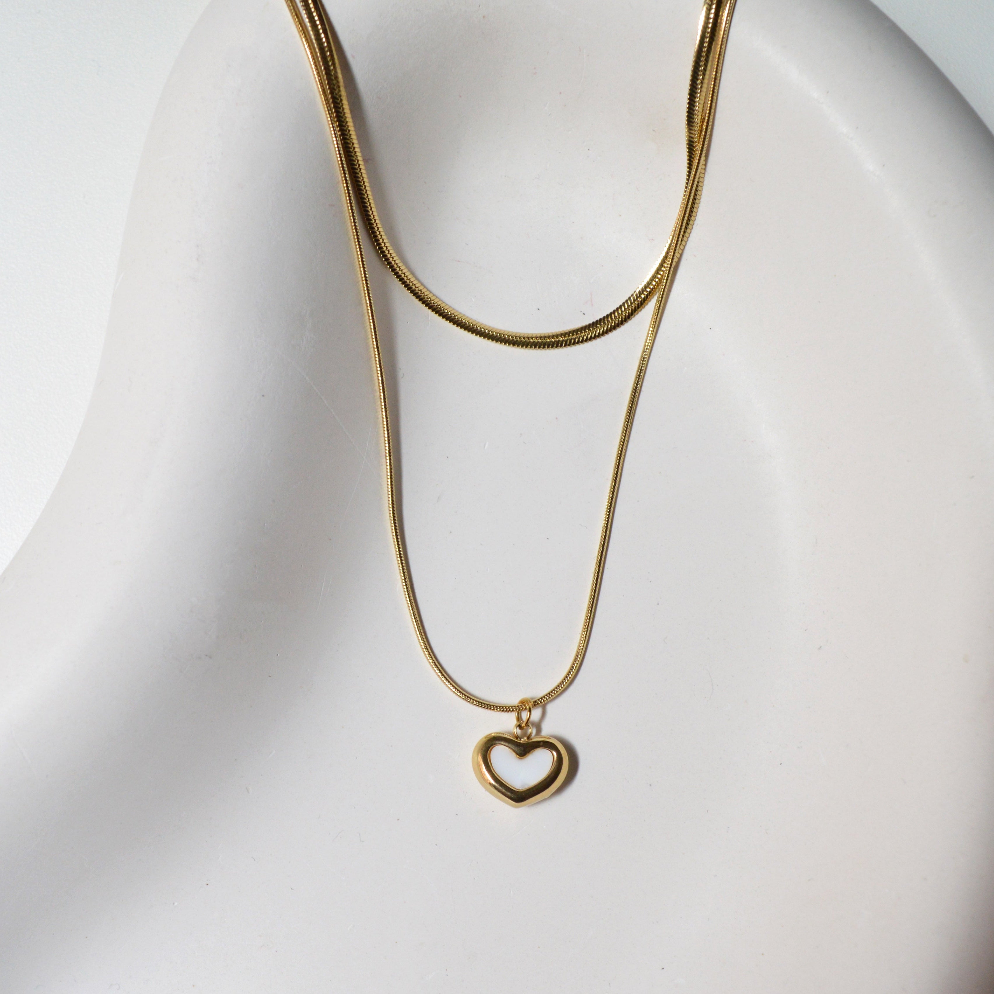 Close-up view of the smooth snake chain and the luminous Mother of Pearl detail inside the gold heart pendant