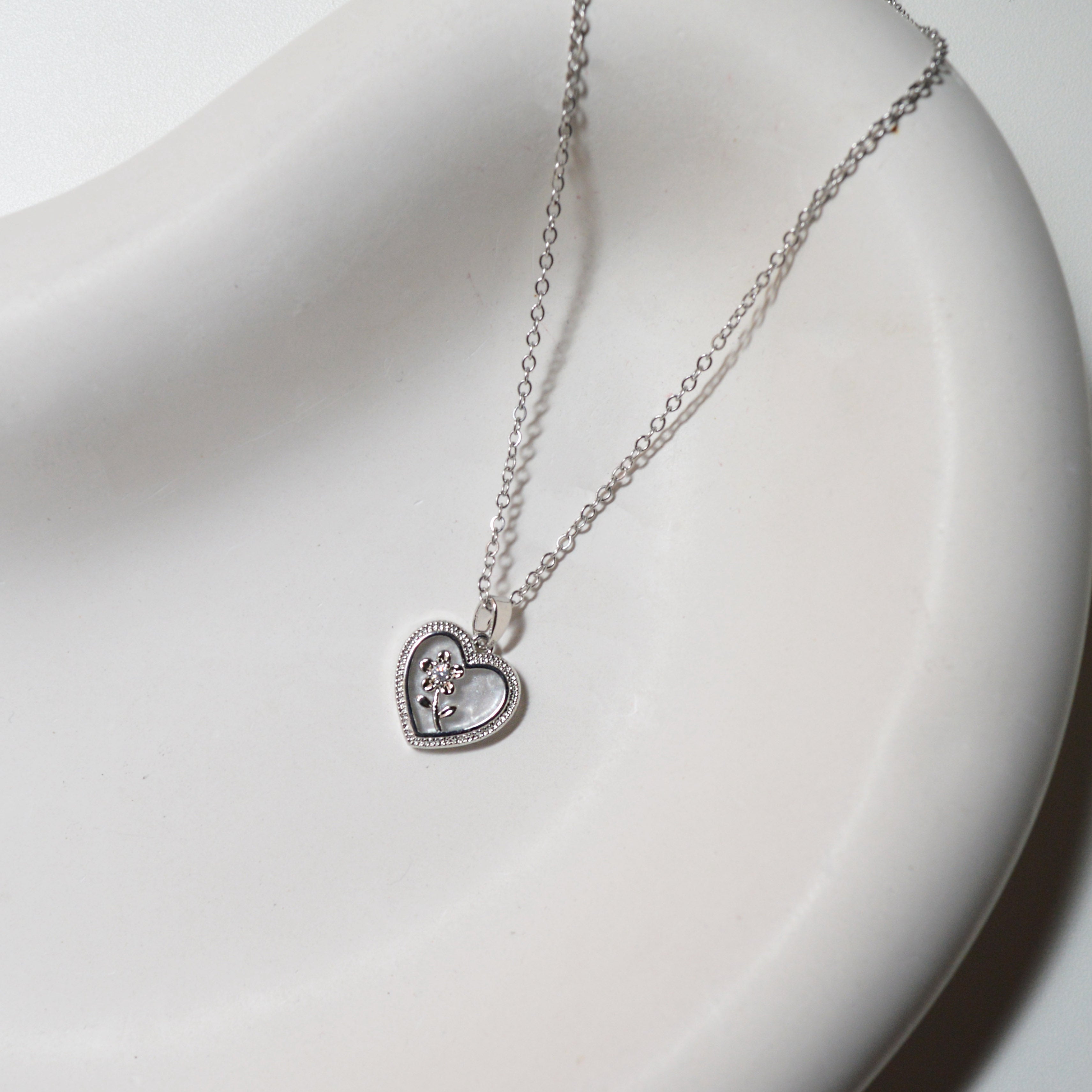 Close-up view of the iridescent Mother of Pearl background and the intricate floral detailing on the Floral Heart Pendant
