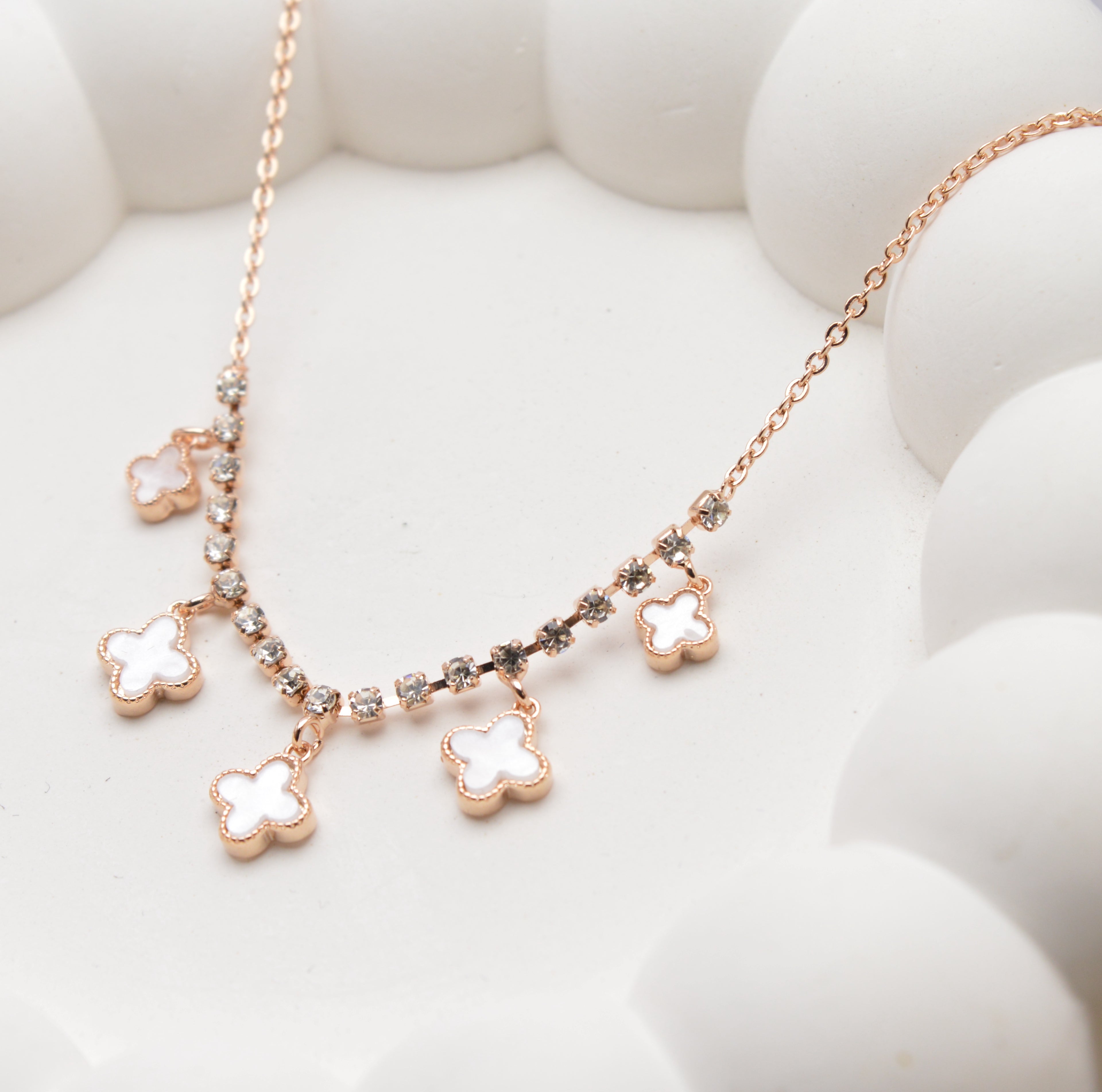 Close-up of rose gold clover necklace with crystal accents