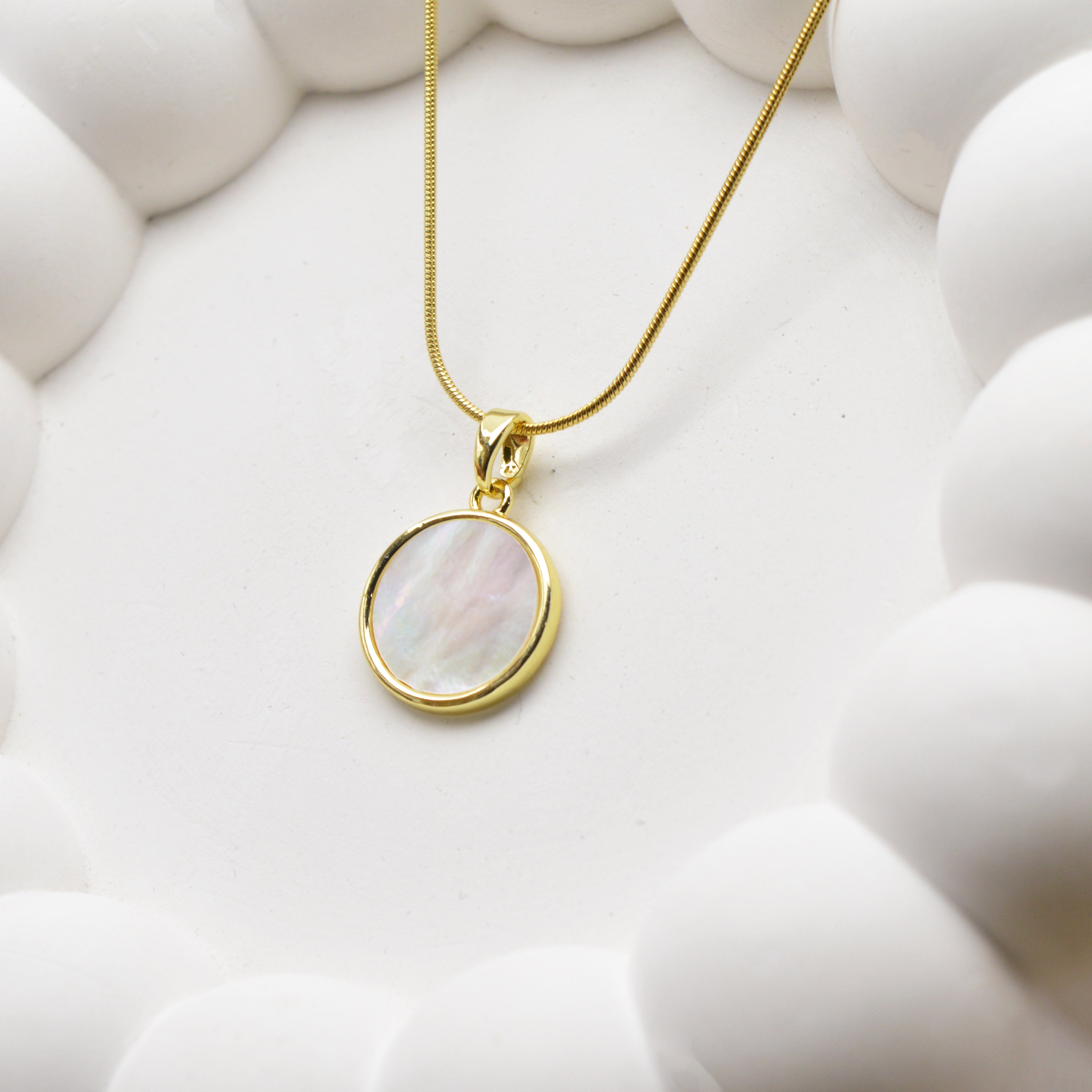 Close-up of round gold tone disc pendant necklace