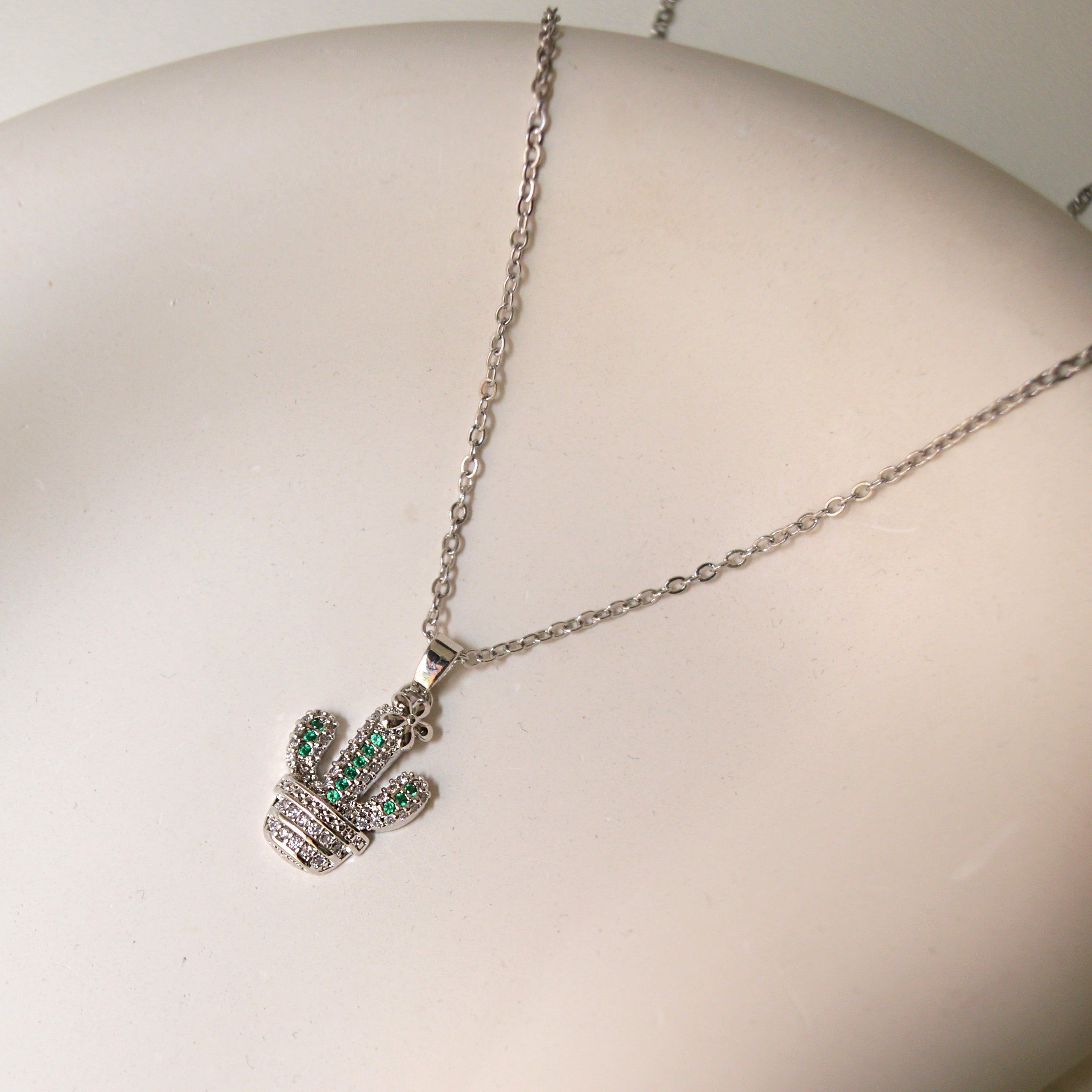 Close-up view of cactus pendant jewelry with green gemstone accents by Civaro
