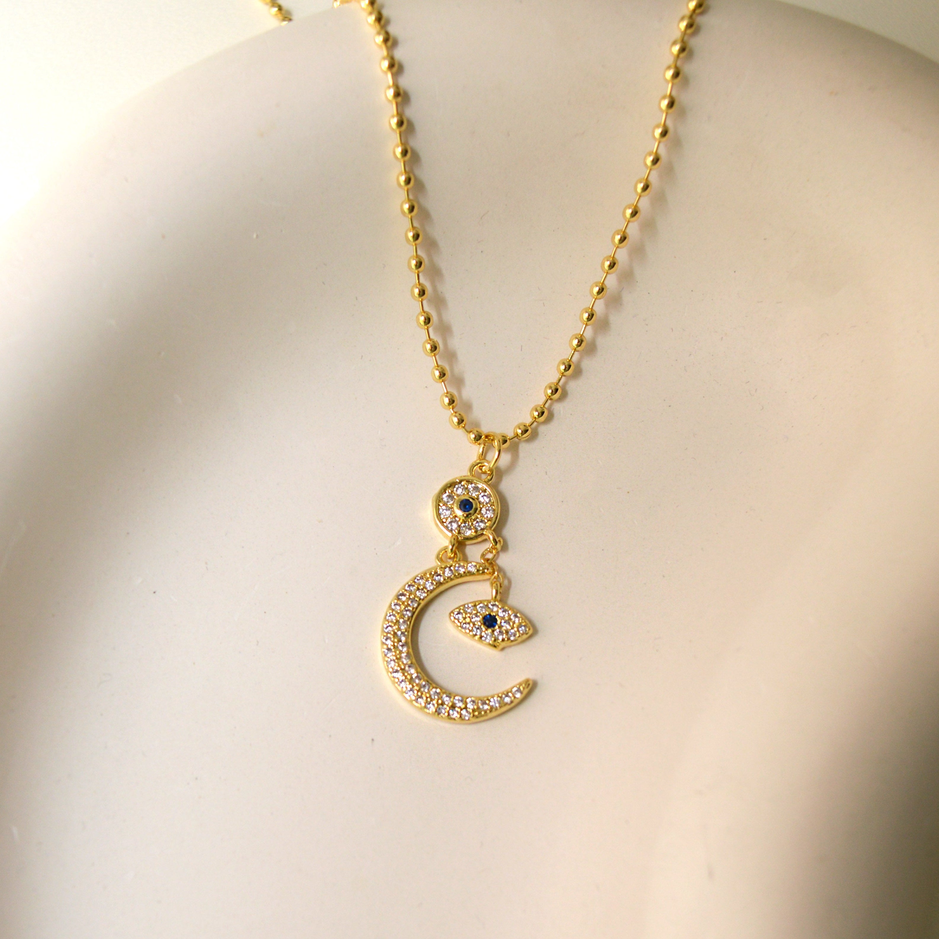 Crescent moon and evil eye necklace with cubic zirconia detailing.
