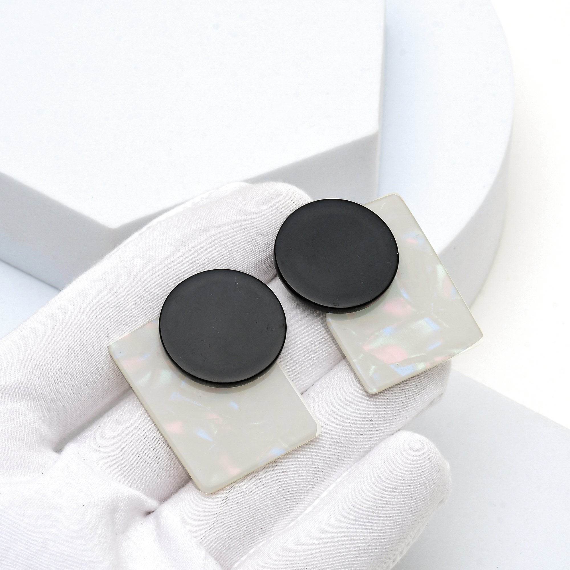 Black and opal geometric earrings displayed in hand