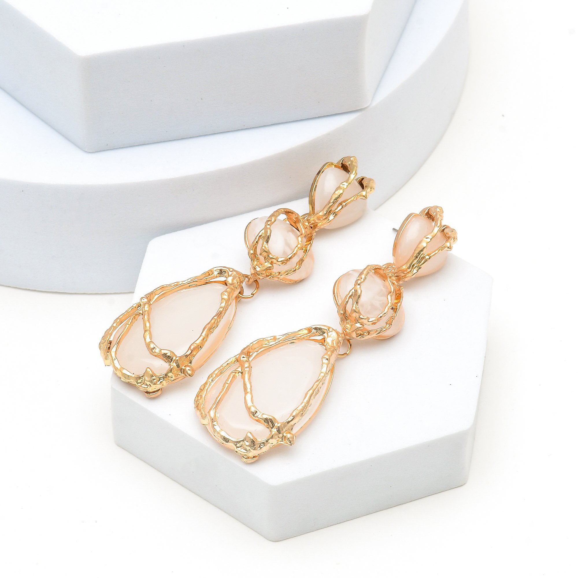 Pair of 18k gold plated organic vine statement earrings with milky white stones on a minimalist background