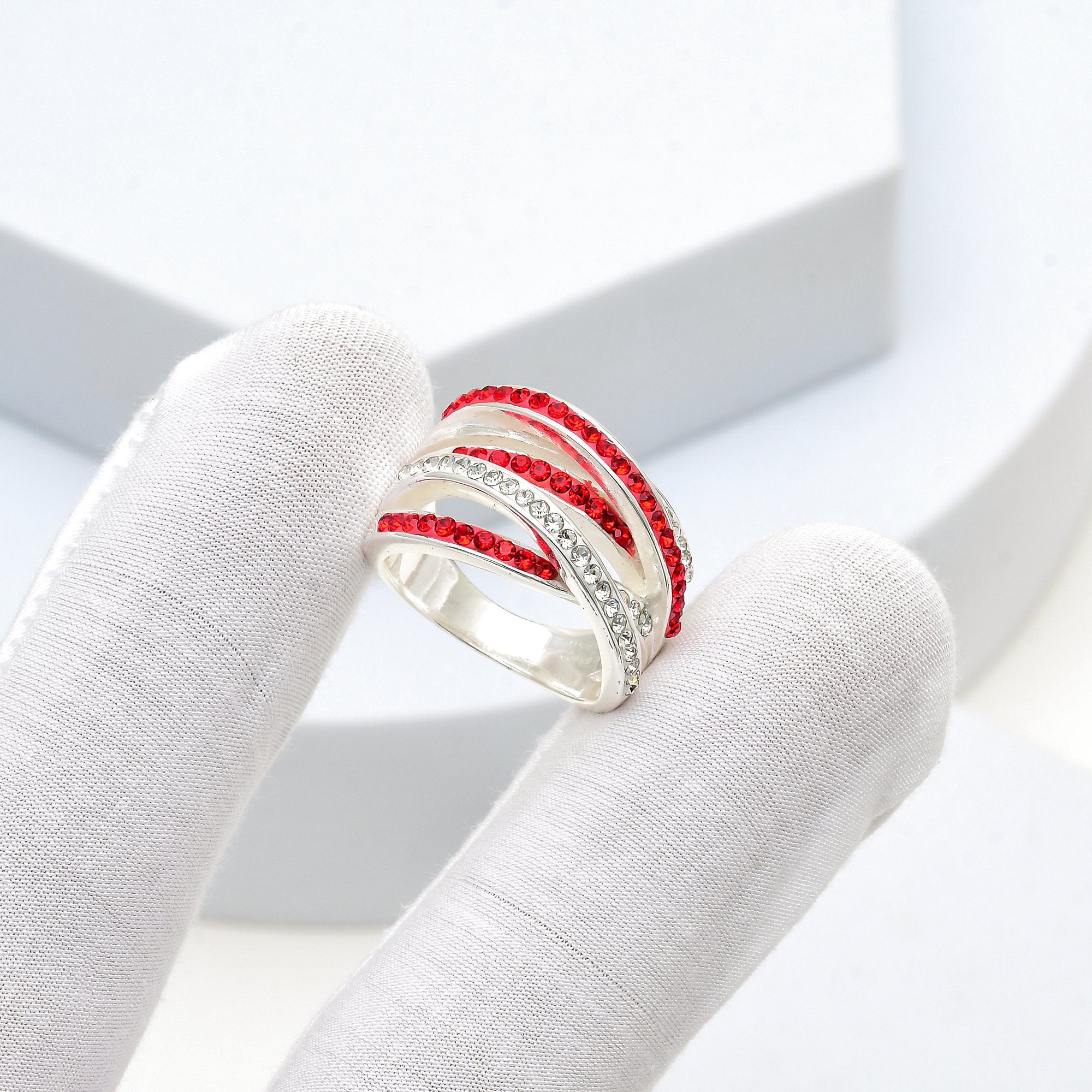 Hand holding the Signature Crimson Crossover ring to capture the premium weight and reflective luster of the silver-plated finish