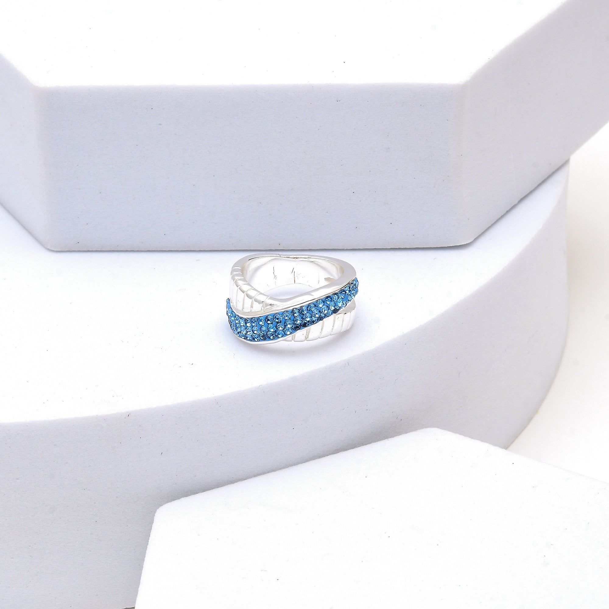 Profile shot of the Signature Azure Crossover ring highlighting the smooth, high-polish silver-tone frame and rhythmic crisscross design
