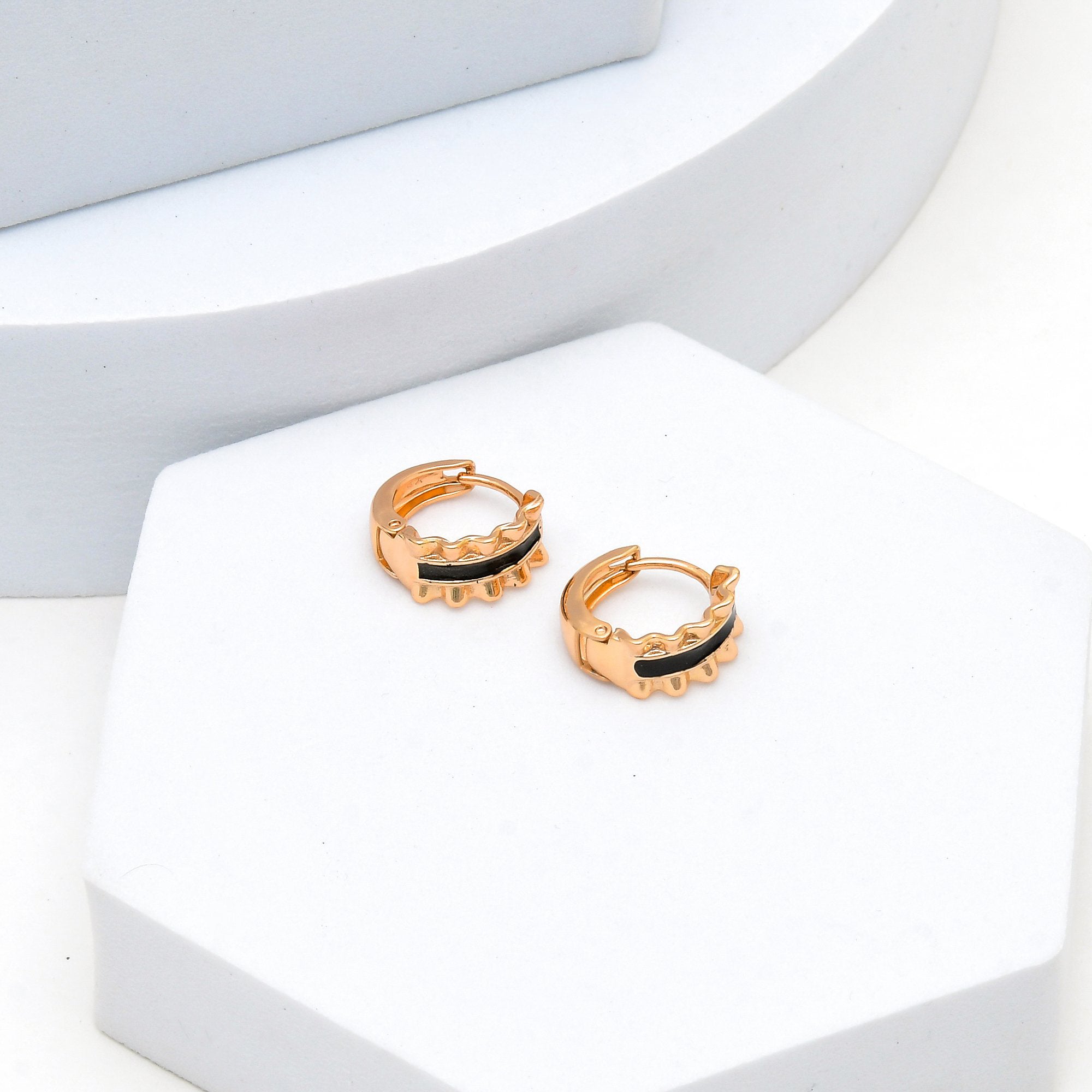 Close-up of black enamel and rose gold tone mini hoops in stainless steel