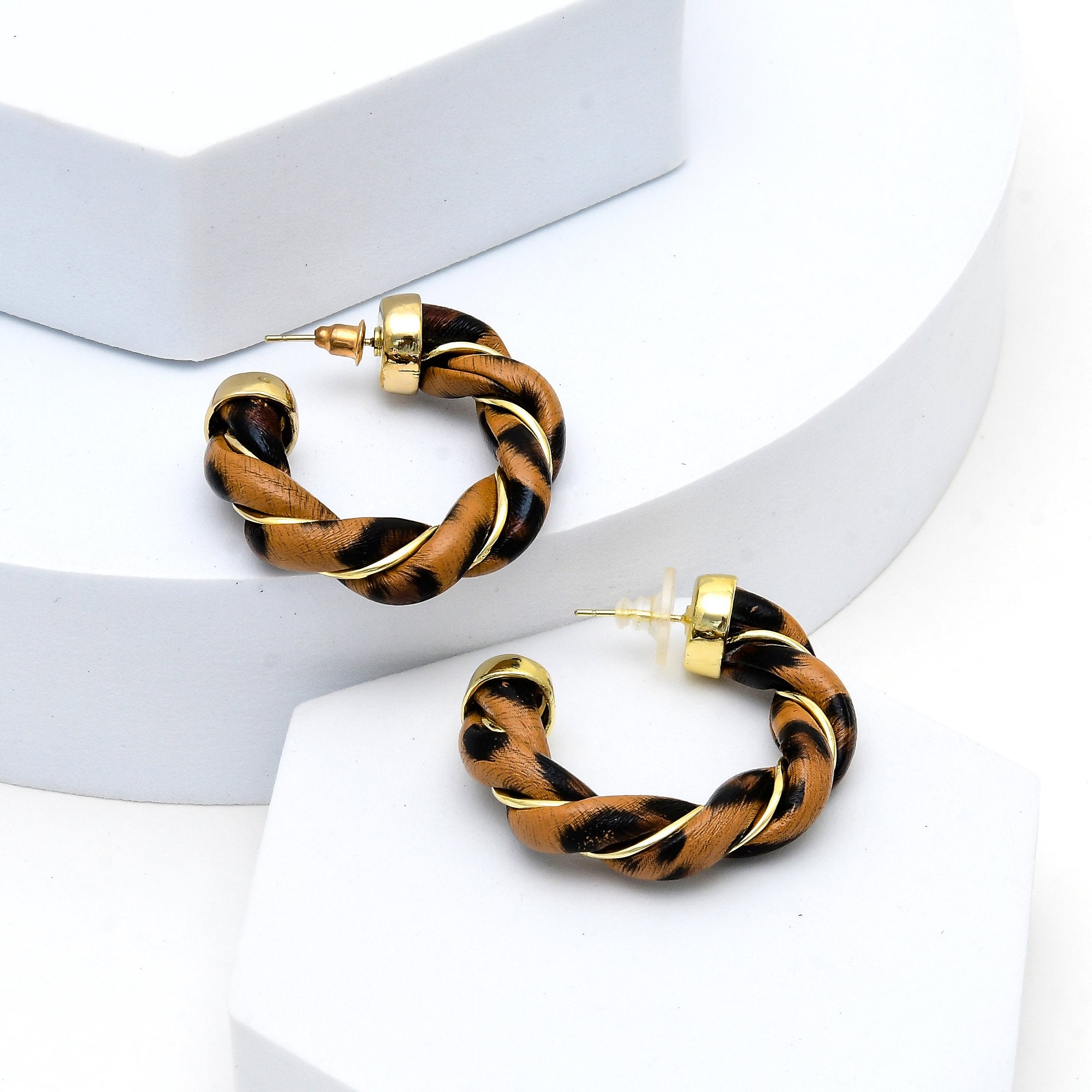     Close-up of sculptural gold hoops reflecting light with textured detailing