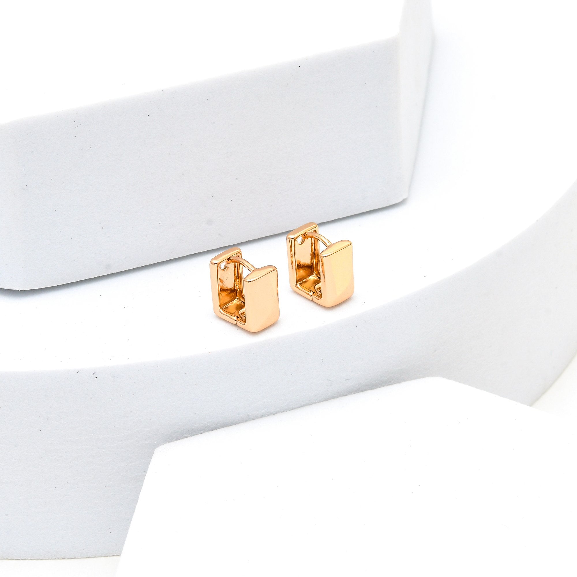Close-up of rose gold geometric huggie earrings with modern minimalist design