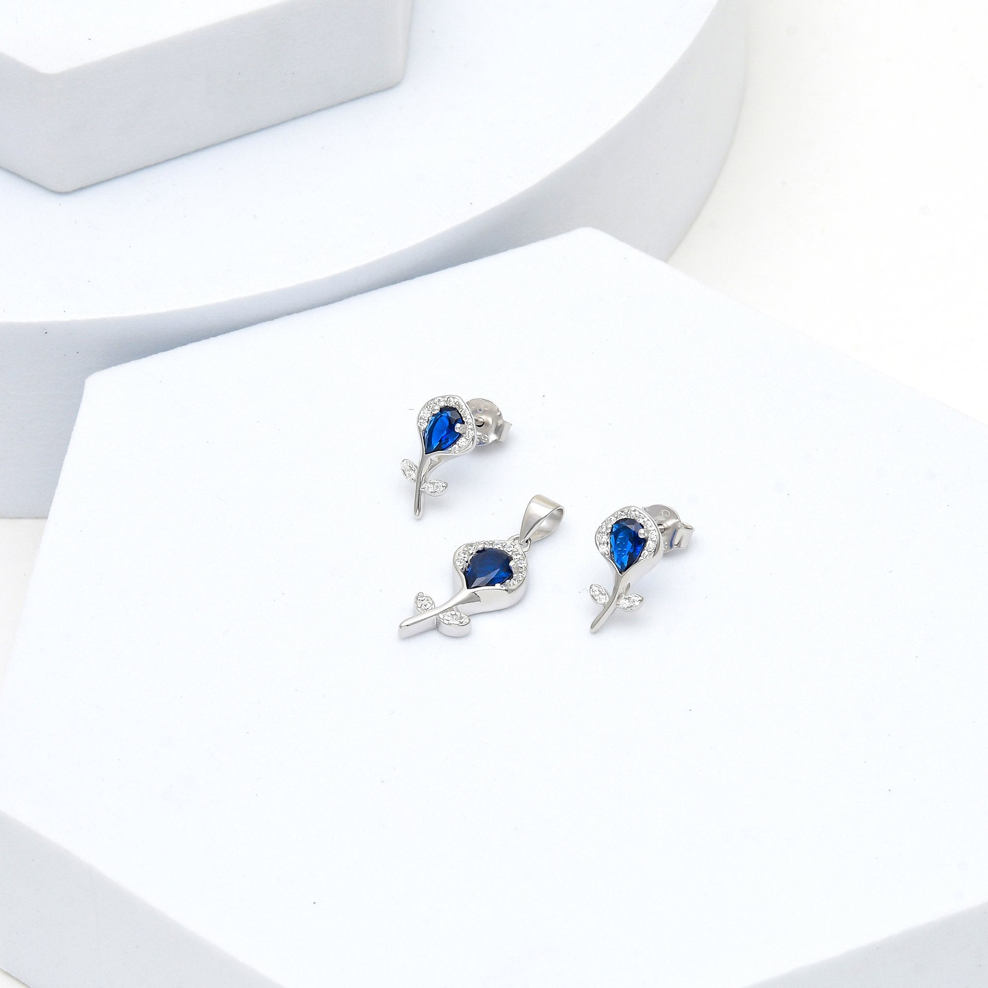 Rhodium plated floral pendant and earring set with deep blue center stone