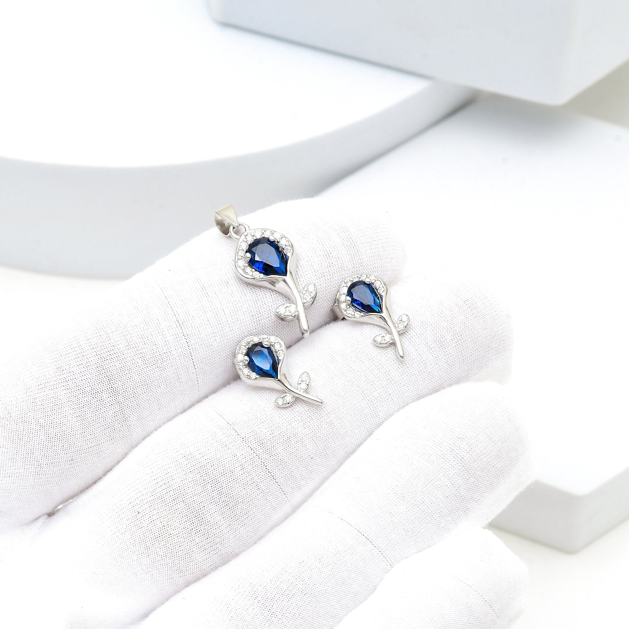 Sterling silver floral jewelry set featuring pendant, earrings and blue stones