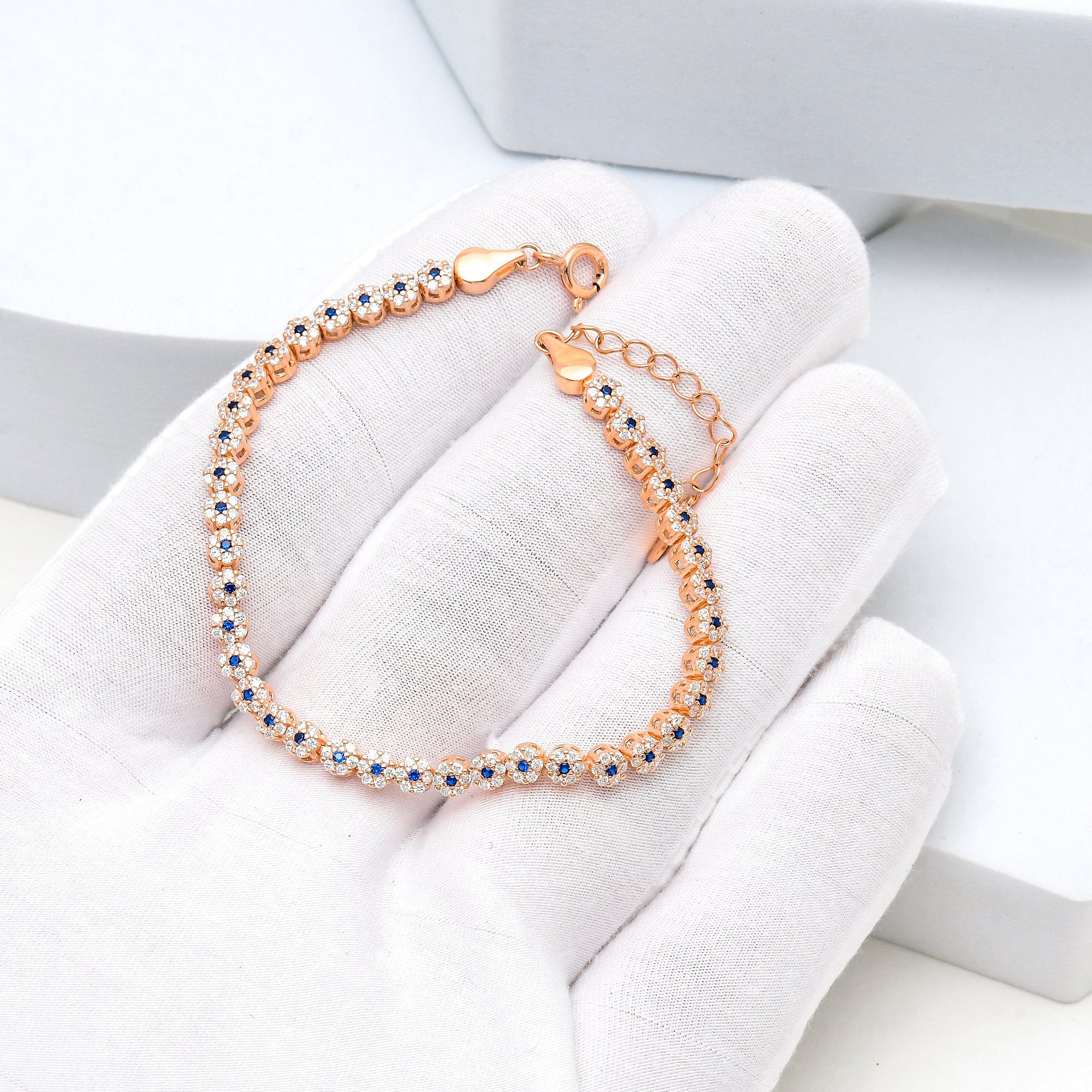 Rose gold tennis bracelet featuring blue and white stones in sterling silver