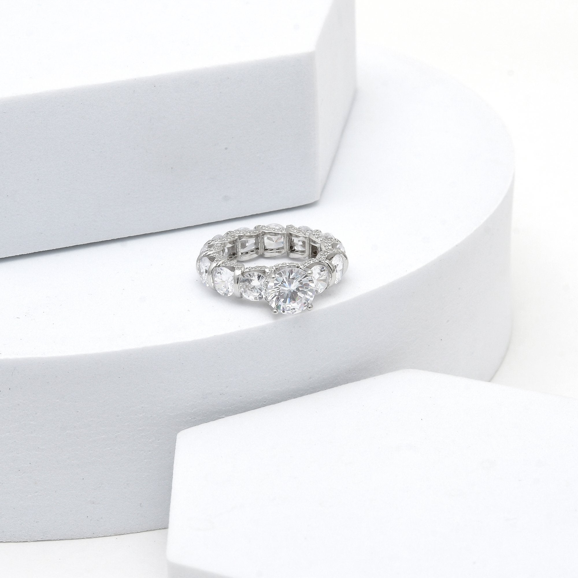 Rhodium plated silver ring with round cut center stone and stone set band