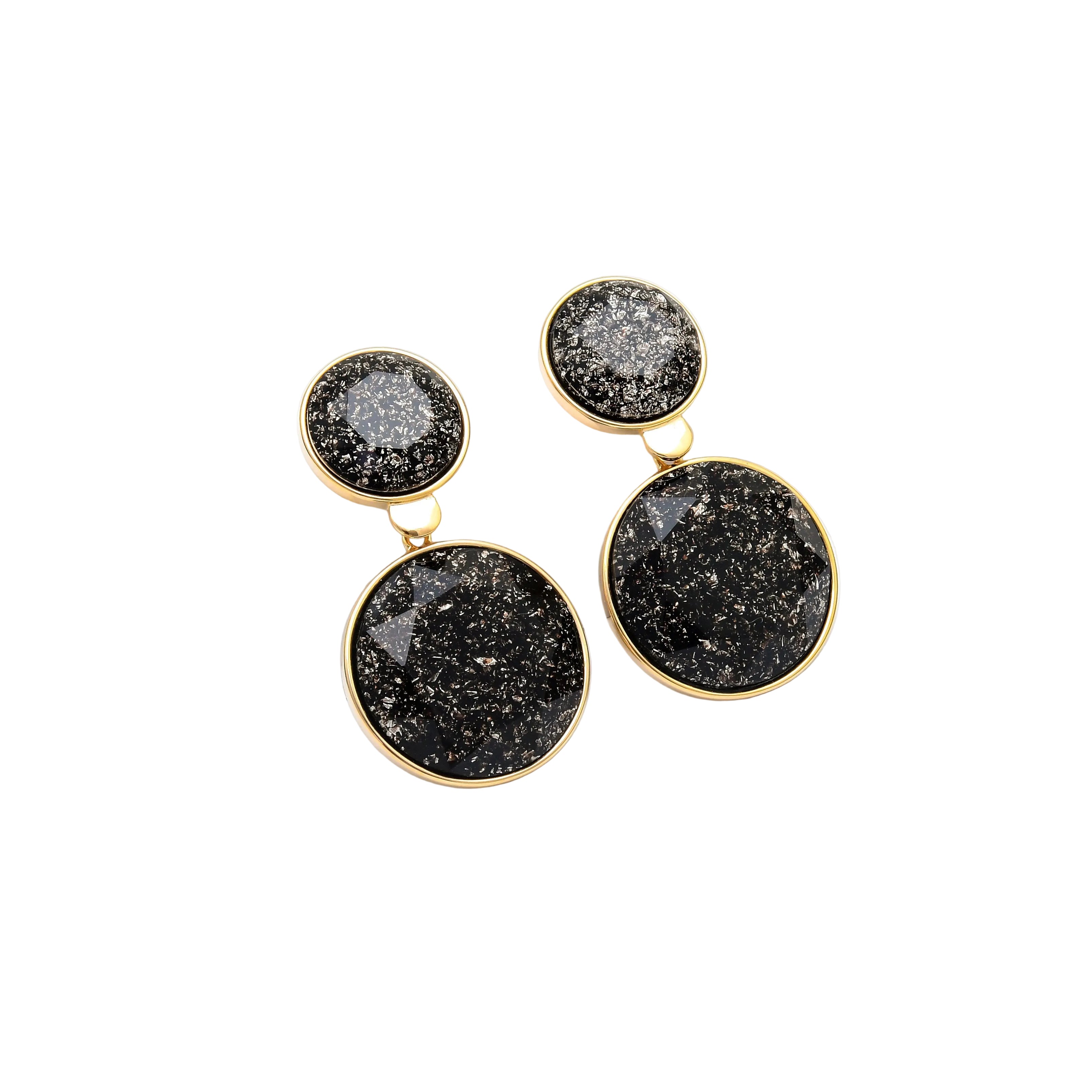 A pair of gold-tone drop earrings with round black druzy stone discs, displayed on a white geometric riser. Black statement drop earrings featuring faceted circular accents with an elegant 18K gold tone finish crafted from premium alloy and brass by Civaro.
