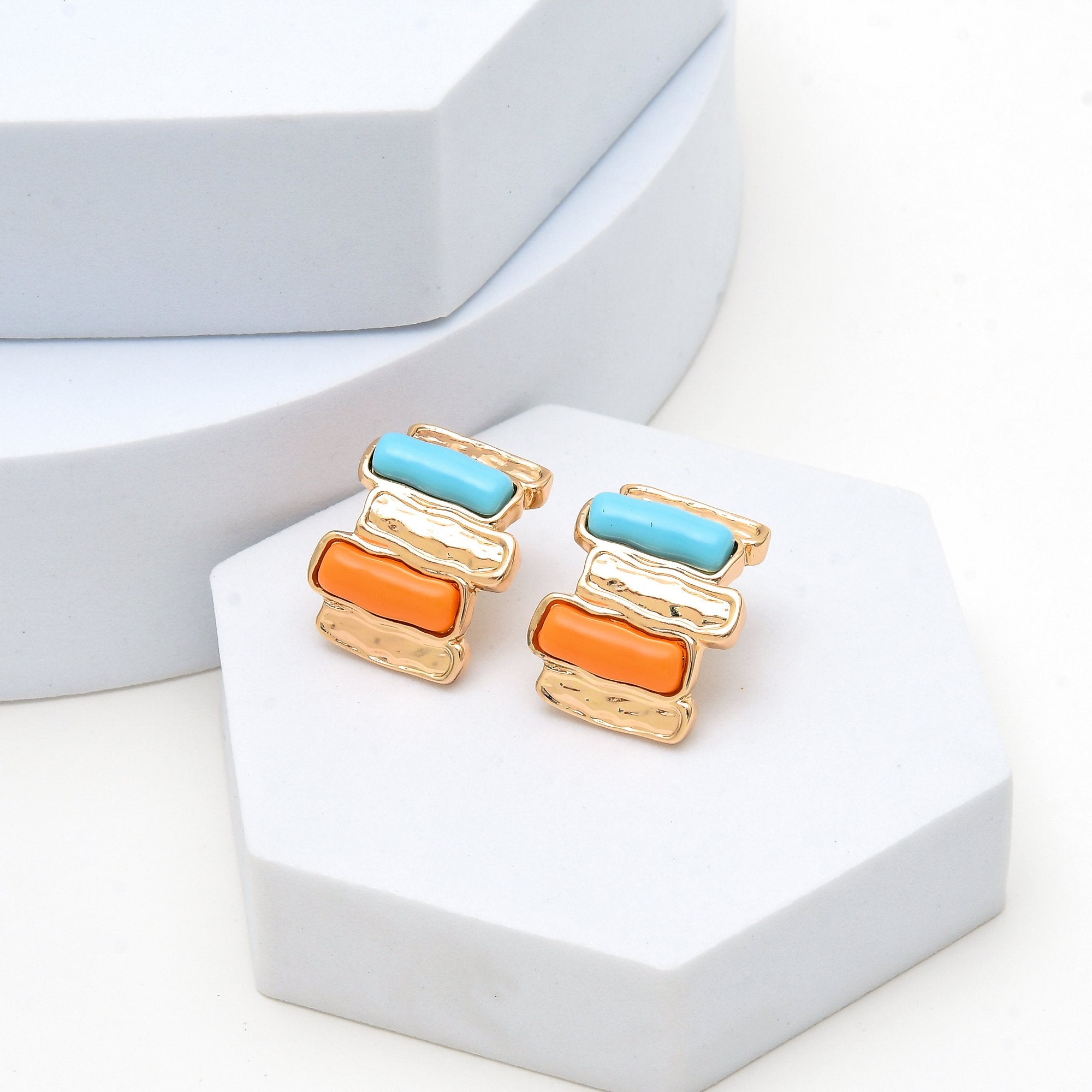 Modern gold earrings featuring textured metal and vibrant color block design.