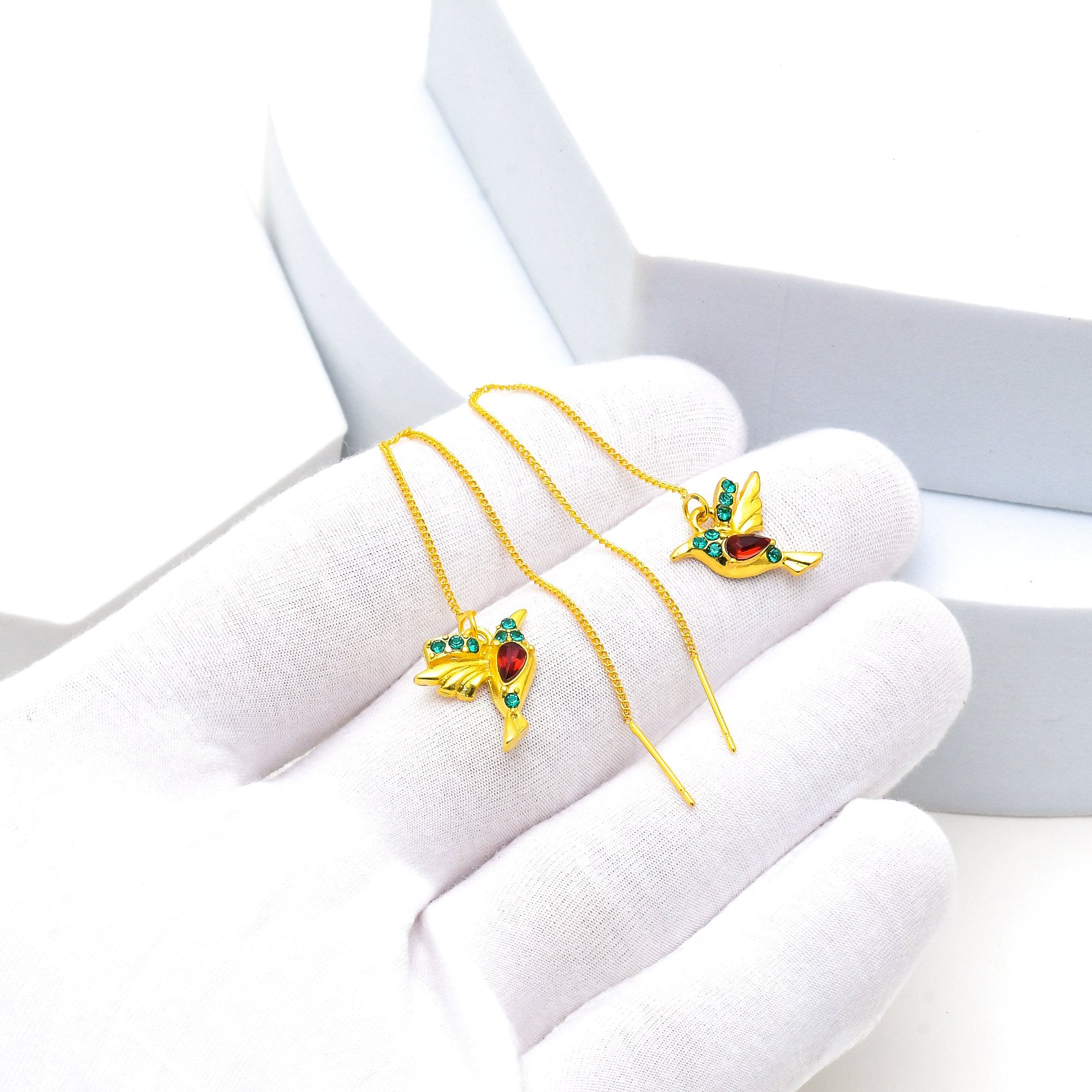     Elegant gold chain threader earrings with bird charm and gemstone accents.