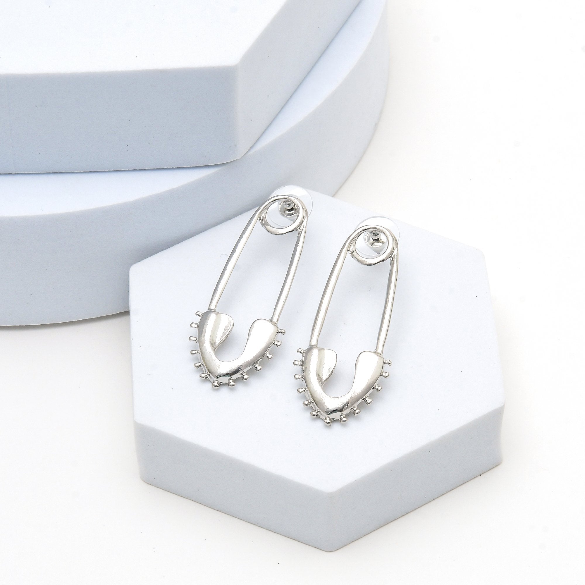     Contemporary stainless steel statement earrings featuring an elongated safety pin design.