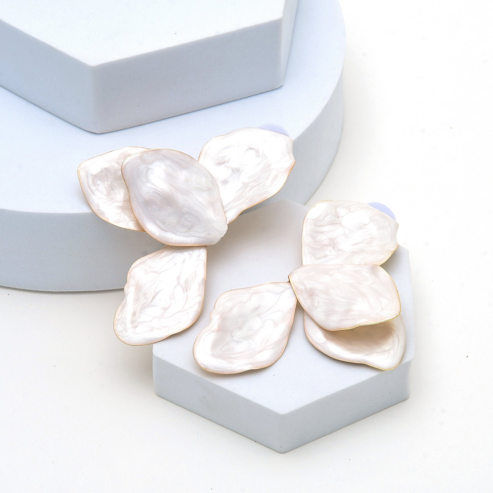 Sculptural floral earrings with pearlescent enamel for elegant occasion styling.