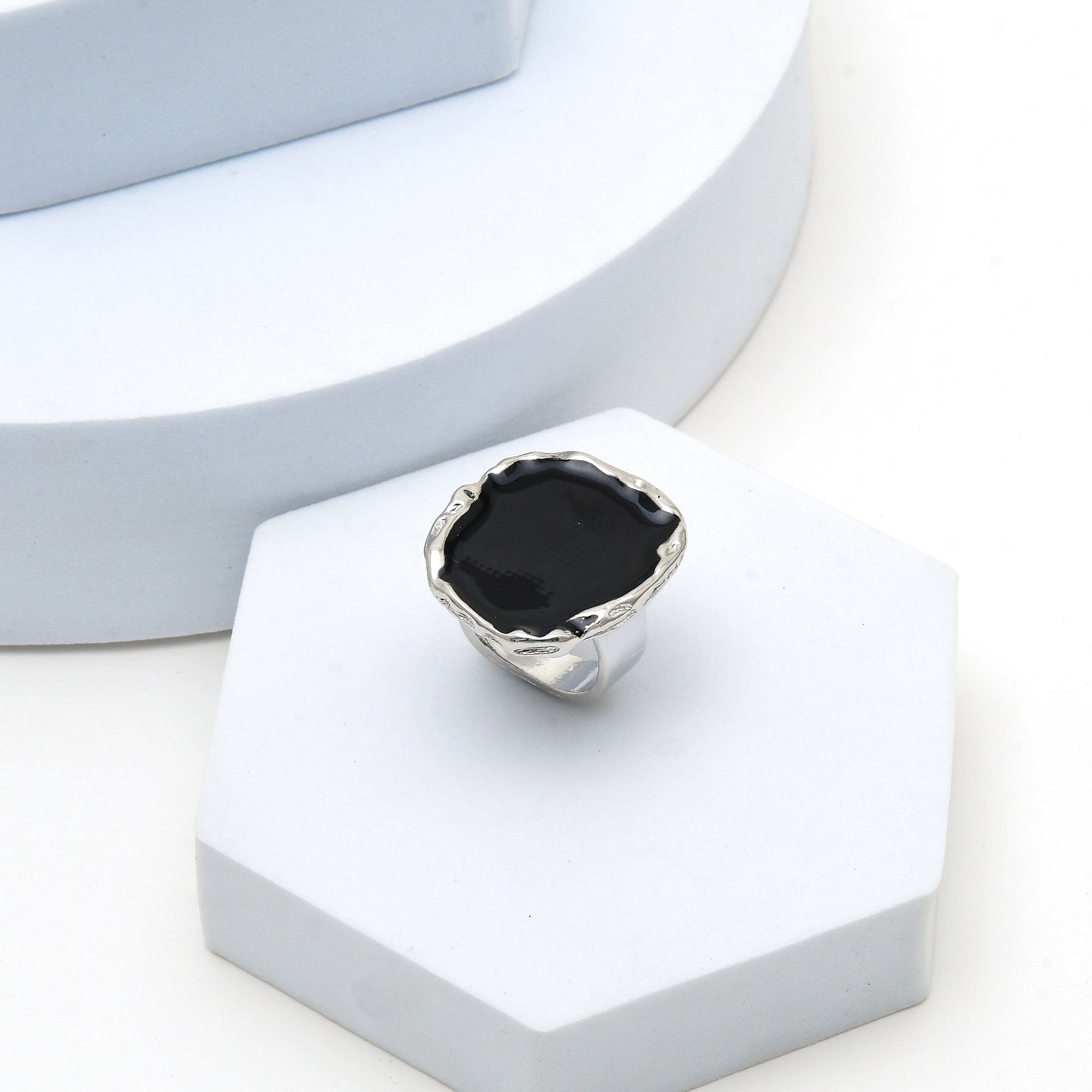 Modern oversized black enamel fashion ring with polished silver finish.