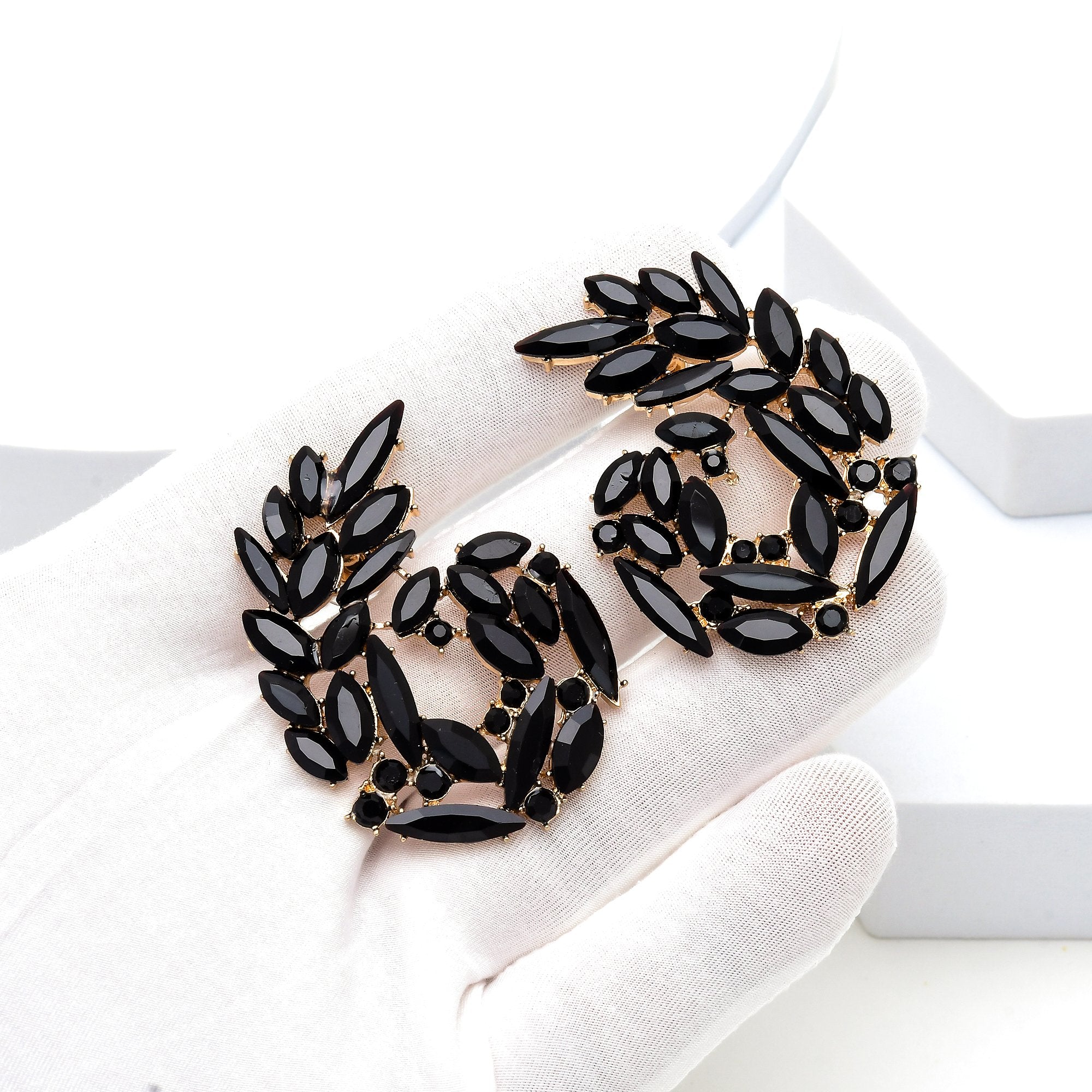 Textured gold earrings crafted from premium brass and alloy with deep ribbed detailing by Civaro.
Black marquise-shaped crystal brooches with gold-tone detailing, displayed on a white gloved hand against a clean white background.