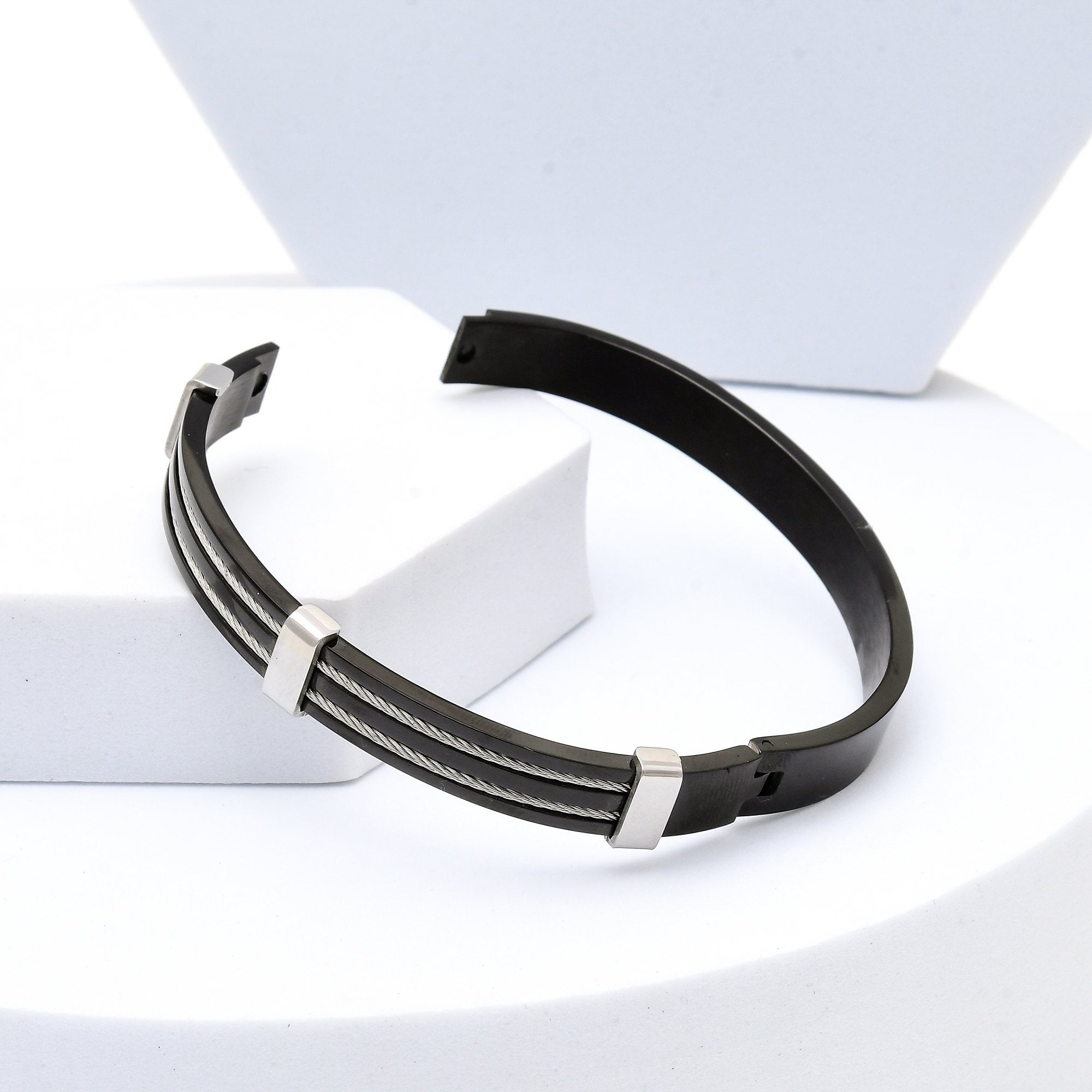 Black and silver bracelet on a white surface with a light gray background