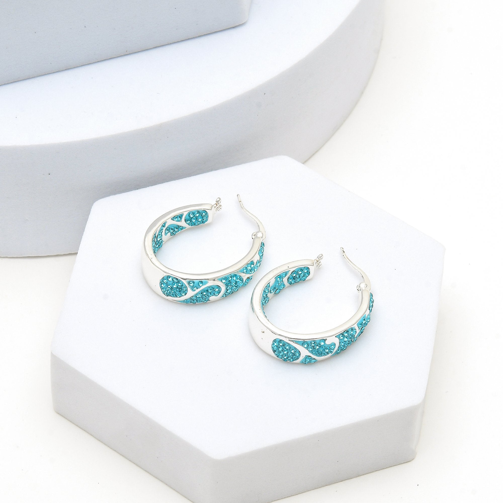 Side profile of the Signature Teal Swirl hoops showcasing the depth of the silver-plated swirl metalwork and crystal intensity