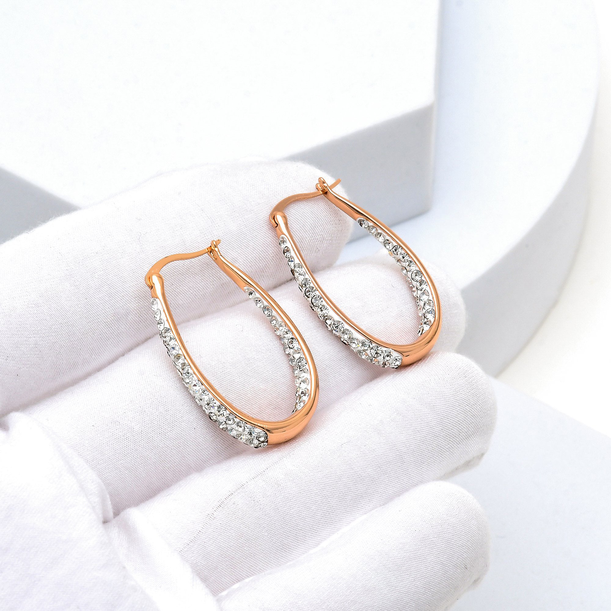 Rose gold crystal hoop earrings displayed in hand