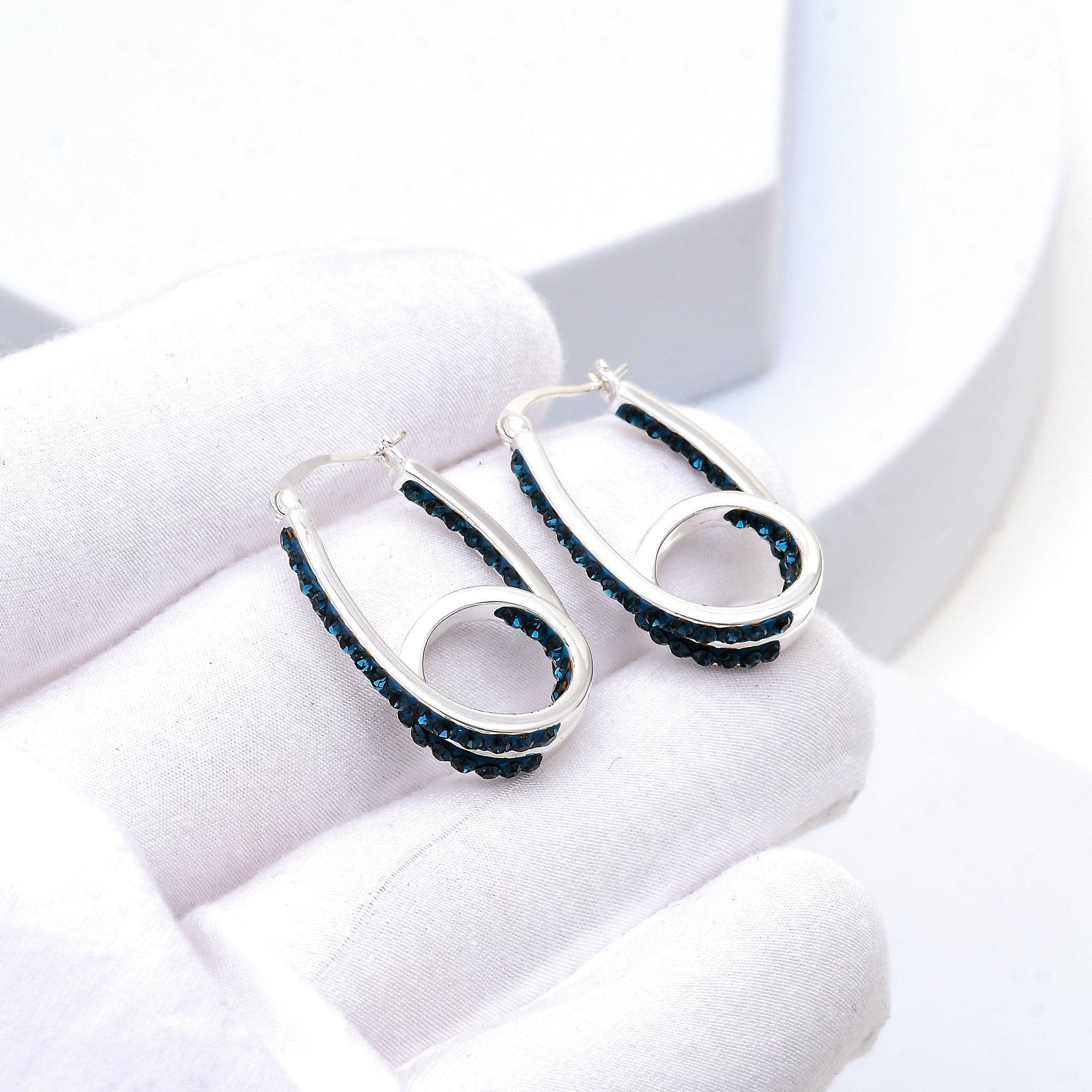 Midnight blue crystal double hoop earrings displayed in hand