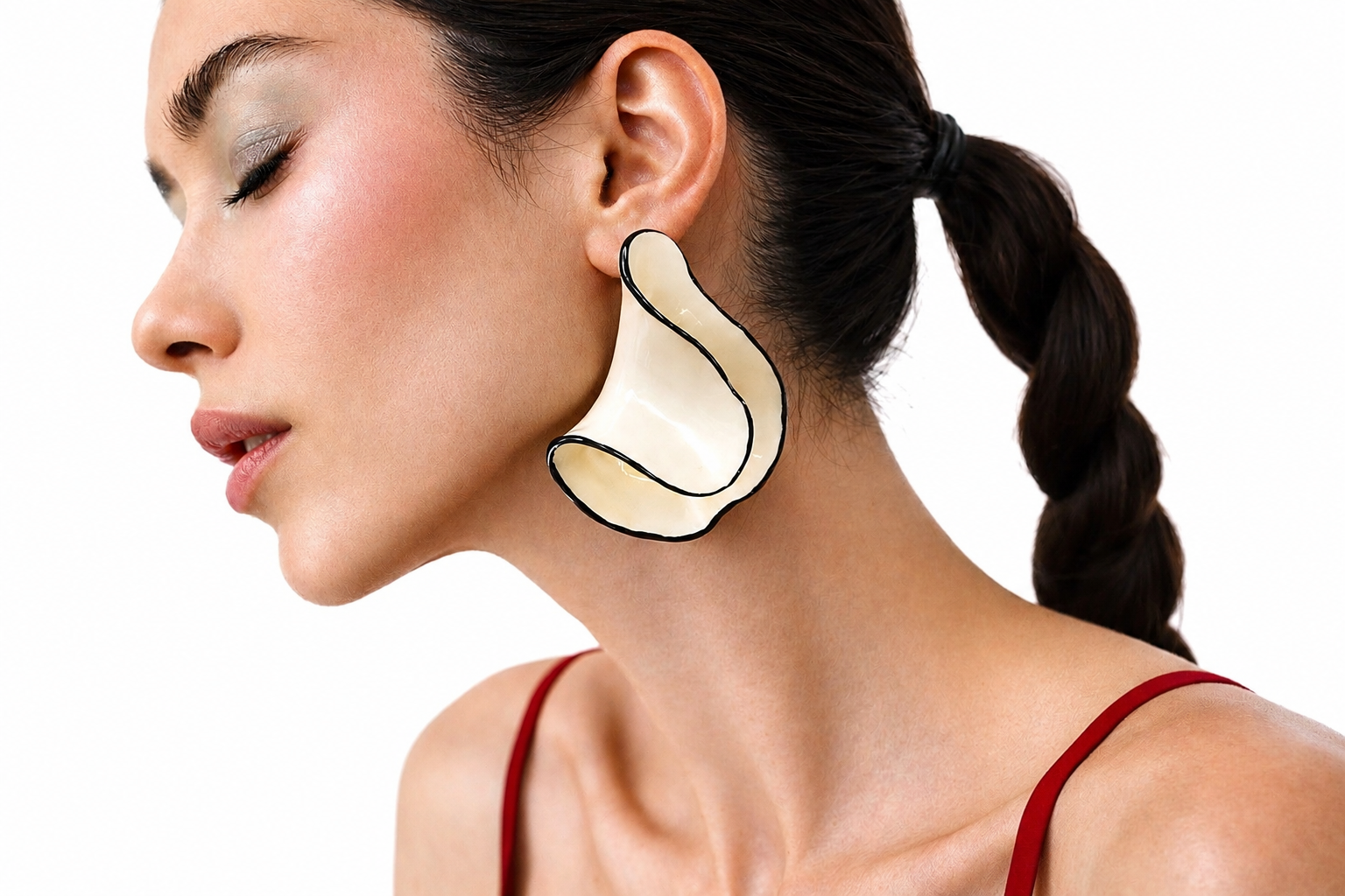 Woman wearing a large, unique earring with a plain background