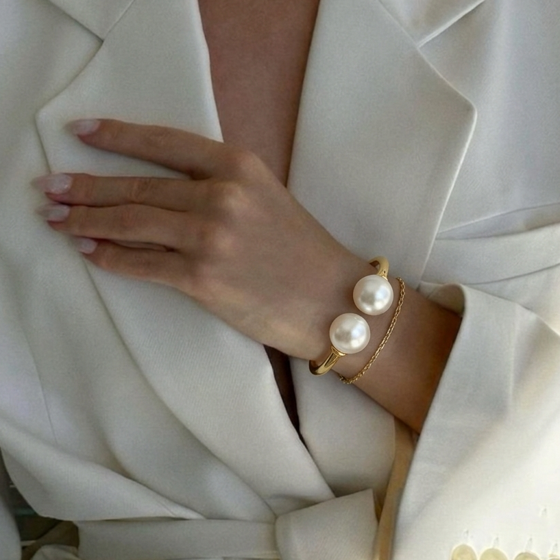 Model styling the gold-toned Juno Double Pearl bangle on the wrist to showcase its architectural scale and premium fit