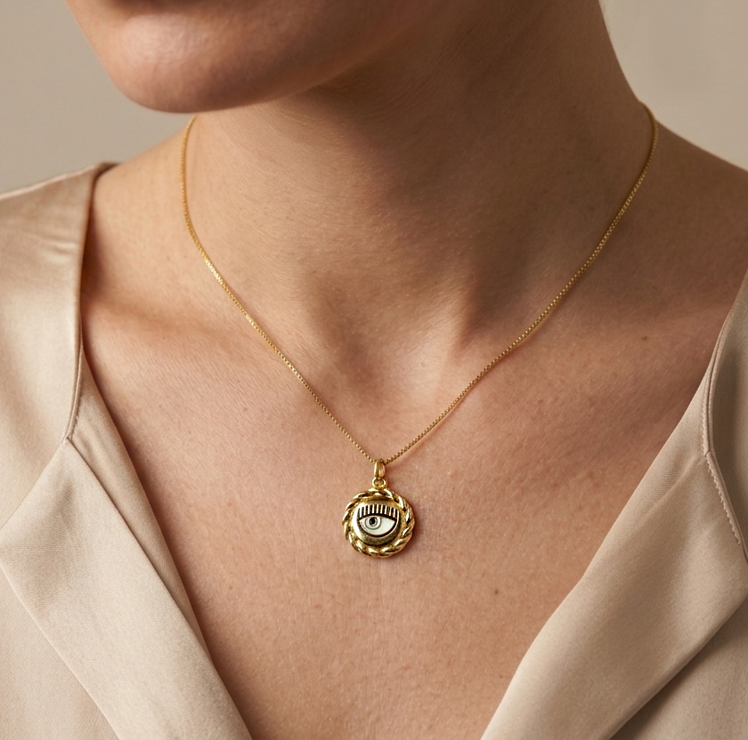 Model wearing gold-tone evil eye pendant necklace on stainless steel chain