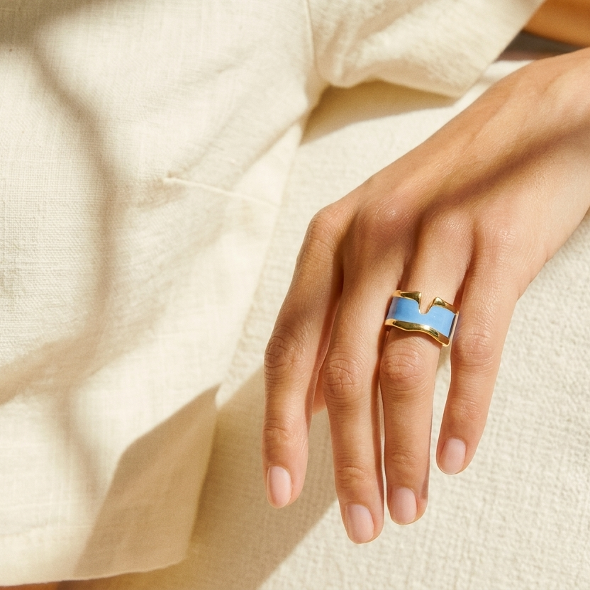 Close-up of the smooth marbled enamel and slightly adjustable open-back design of the Cyan Serene ring held in hand