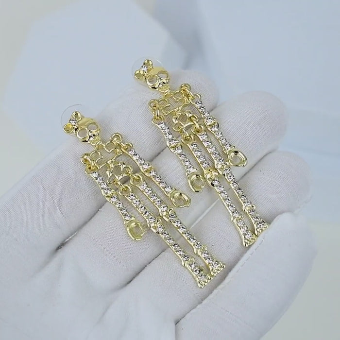 video of A close-up side profile of a woman wearing a delicate gold skeleton-shaped dangle earring with small clear stones, paired with a black satin high-neck top against a light gray background by Civaro