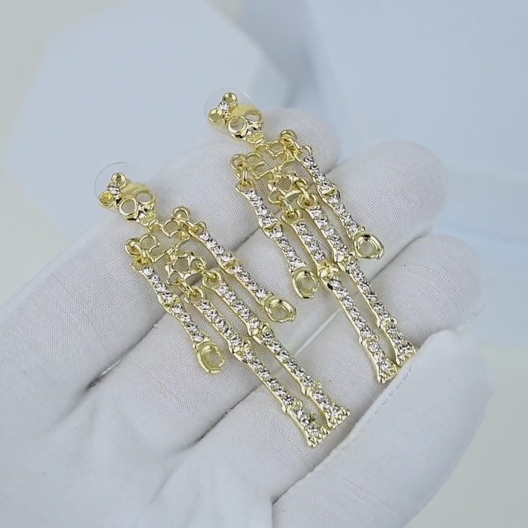 video of A close-up side profile of a woman wearing a delicate gold skeleton-shaped dangle earring with small clear stones, paired with a black satin high-neck top against a light gray background by Civaro