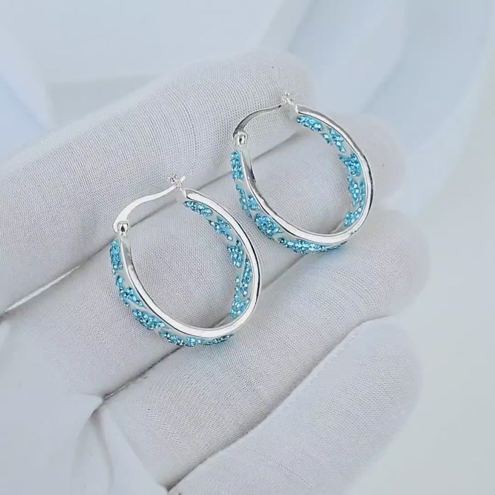 Video showcasing the intricate handcrafted swirl metalwork and the light-catching brilliance of the teal crystals on the Signature Teal Swirl hoops