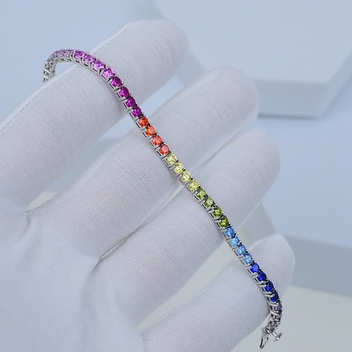 Multi-colour sterling silver tennis bracelet with CZ stones shown in motion highlighting rainbow reflections. Close-up wrist movement showcasing vibrant CZ tennis bracelet in 925 silver
Minimal luxury rainbow tennis bracelet rotating in light to reveal multi-colour sparkle