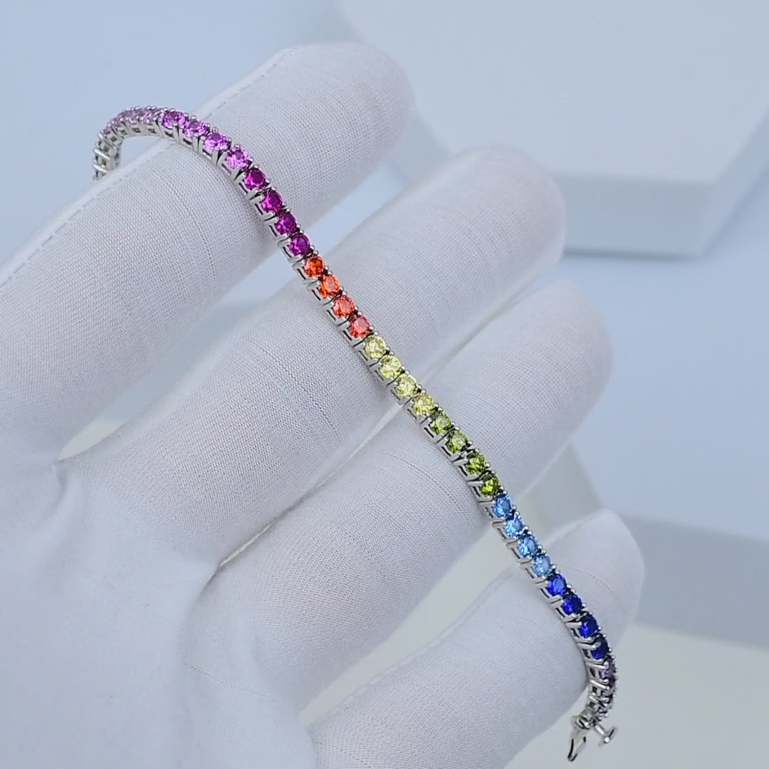 Multi-colour sterling silver tennis bracelet with CZ stones shown in motion highlighting rainbow reflections. Close-up wrist movement showcasing vibrant CZ tennis bracelet in 925 silver
Minimal luxury rainbow tennis bracelet rotating in light to reveal multi-colour sparkle