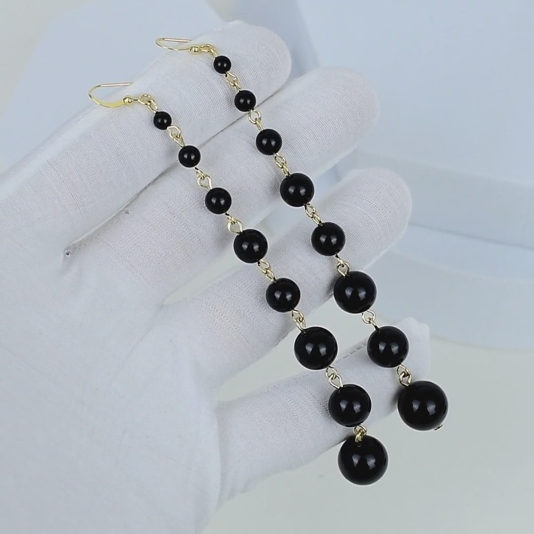 Long beaded pearl earrings featuring polished black pearls and gold tone stainless steel hardware for elegant everyday styling by civaro